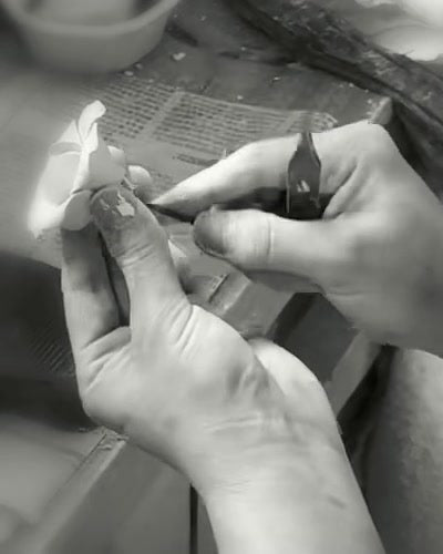 Monochrome detail of hands shaping a clay flower