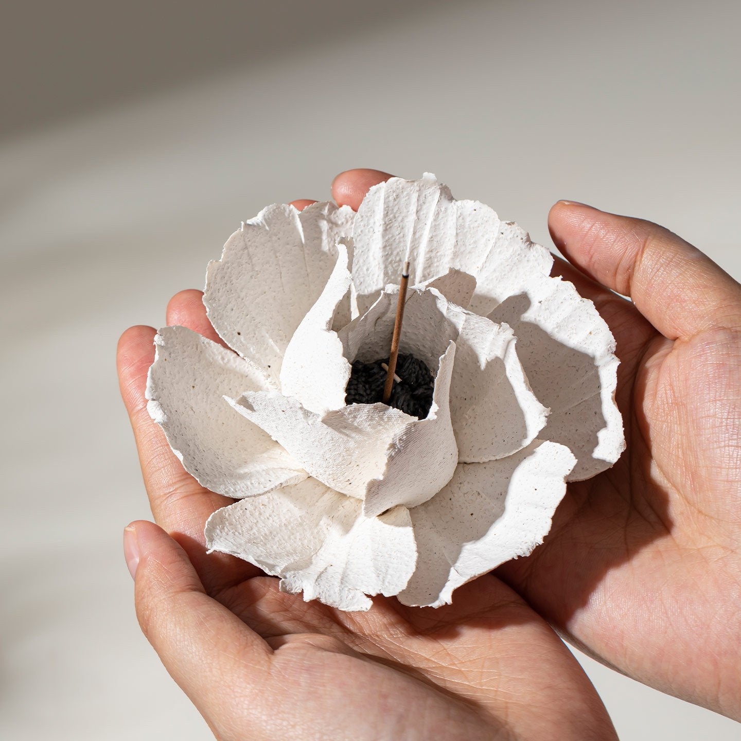 A finished ivory porcelain flower held gently in two hands